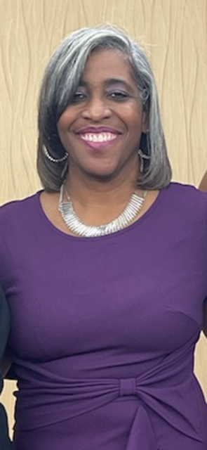 Dr. Tygere Charles smiling in a purple dress with silver jewelry